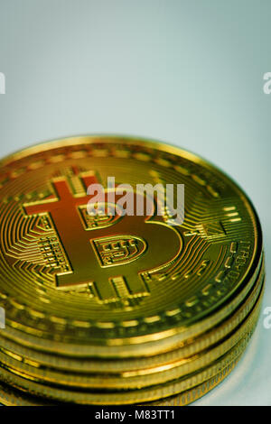 closeup of a pile of bitcoins against an a pale gray background, with some blank space on top Stock Photo