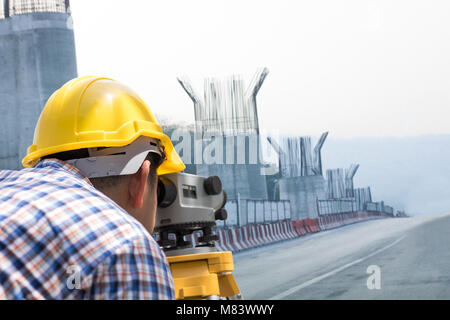 Engineer and worker looking at  level-measuring instrument on road and building bridge Stock Photo