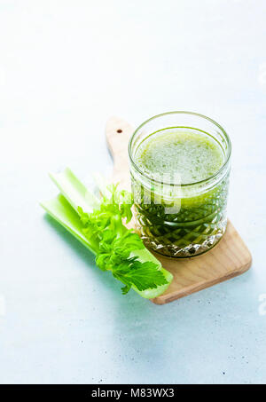 Freshly squeezed celery juice in a glass on a wooden small board on the table. concept and recipe for a healthy diet Stock Photo