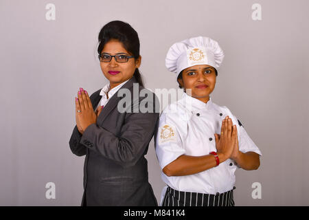 Female chef and staff in a restaurant standing with Namaste greeting Stock Photo