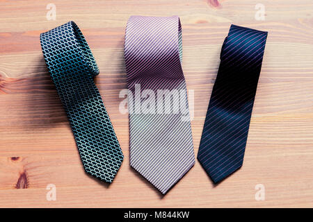 three men's tie rolled into a roll on a wooden background Stock Photo