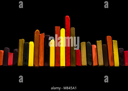 Lined up pastel crayons as a graph on black background Stock Photo