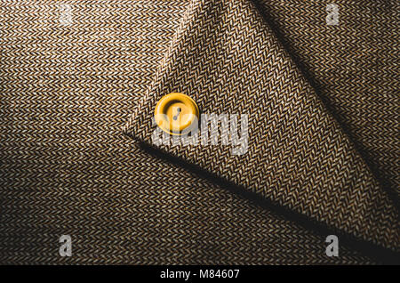 Yellow button on a folded brown textile Stock Photo