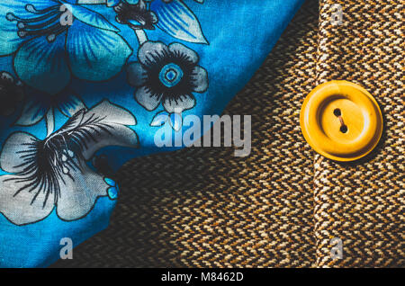 Blue scarf with flower pattern and yellow button on brown textile background Stock Photo
