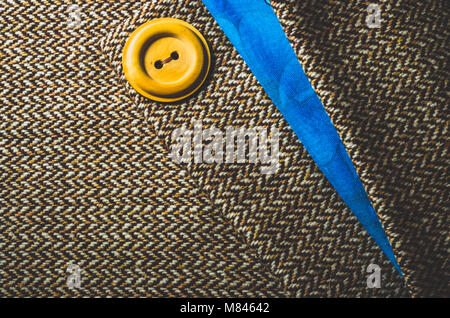 Yellow button on folded brown and blue fabric Stock Photo
