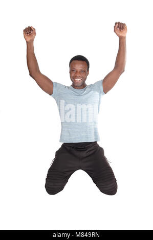 A young handsome African American man kneeling on the floor with his fists and smiling of victory and success, isolated over white Stock Photo