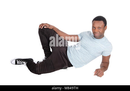A young good looking African American man sitting on the floor, resting, in truck pants and t-shirt, isolated for white background Stock Photo