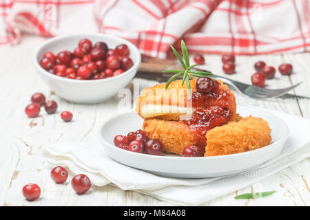 Baked Camembert (brie) with fresh berries and cranberry sauce with rosemary on a white plate. Gourmet appetizer. Breakfast. Selective focus Stock Photo