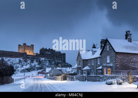 Bamburgh Castle and village in winter snow, Northumberland, England. Winter (February) 2018. Stock Photo