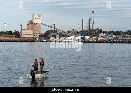 Two men fishing in a small boat (a Tinny) on Sydney harbour near White Bay. In the background is the Glebe Island silos that hold dry cement. Stock Photo