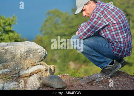 Mature tourist watching the tortoise on the Heaven island near Marmaris, Turkey Stock Photo