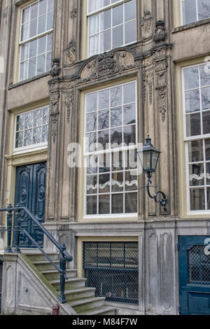 typical vintage classic house on canals in Amsterdam with big stairs windows, and lantern Stock Photo