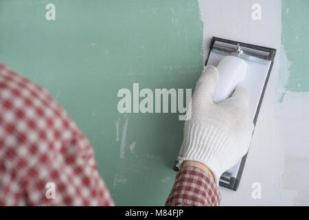 Contractor sanding the drywall mud using sand trowel Stock Photo