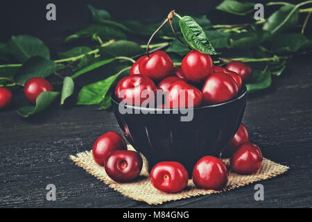 Fresh cherries in bowl on old black wooden table(selective focus). Stock Photo