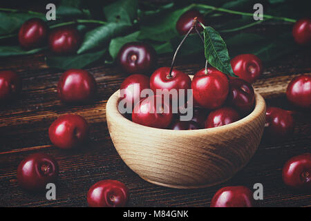 Fresh cherries in bowl on old brown wooden table(selective focus). Stock Photo