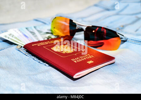 Red russian Passport with money bills and glasses on jeans. The concept of travel Stock Photo