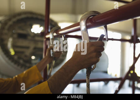 Male worker climbing scaffolding at solar station Stock Photo