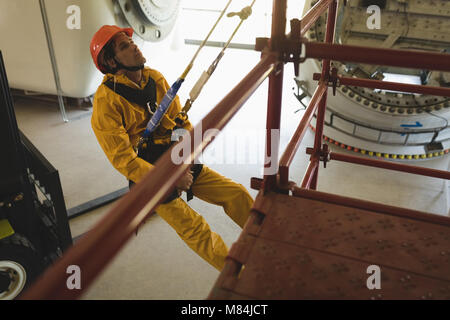 Male worker climbing scaffolding at solar station Stock Photo