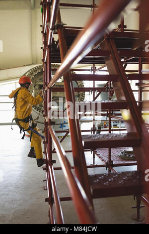 Male worker climbing scaffolding at solar station Stock Photo