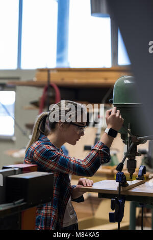 Female carpenter using vertical drill machine Stock Photo
