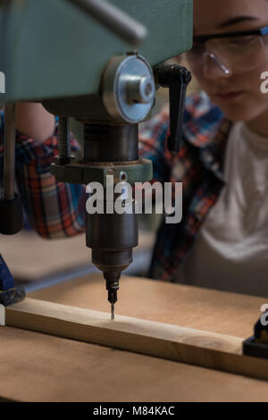 Female carpenter using vertical drill machine Stock Photo