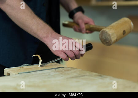 Male carpenter using chisel with hammer on a piece of wood Stock Photo