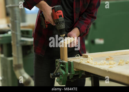 Male carpenter using drill machine at workshop Stock Photo