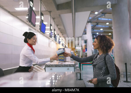 Airline check-in attendant handing passport to commuter Stock Photo