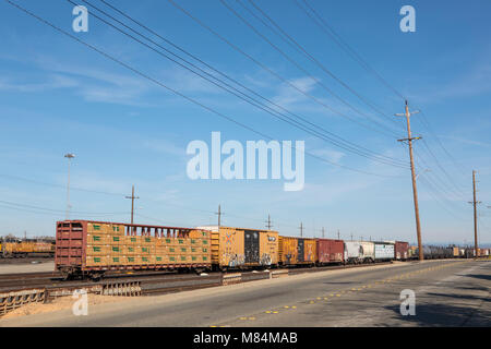 Back end of a long goods train in the shunting yards of Roseville California. Pacific Union rolling stock disappearing into the distance. Stock Photo