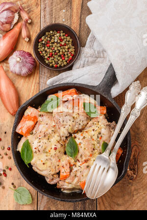 Rabbit stewed with vegetables and herbs in a cast iron skillet. Meat, carrots, shallots, garlic, and Basil. Seasonings. Dinner in a rustic style. Sele Stock Photo