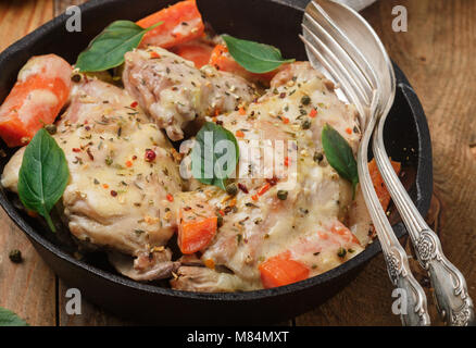 Rabbit stewed with vegetables and herbs in a cast iron skillet. Meat, carrots, shallots, garlic, and Basil. Seasonings. Dinner in a rustic style. Sele Stock Photo