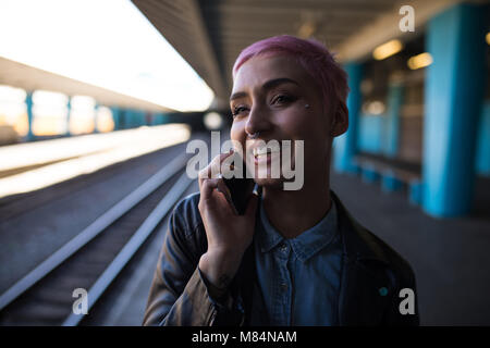 Stylish woman talking on mobile phone at railway station Stock Photo
