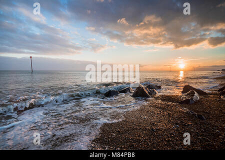 Sunset on a pebble beach with views towards Bognor Regis pier, Selsey and the Isle of Wight, West Sussex, UK Stock Photo