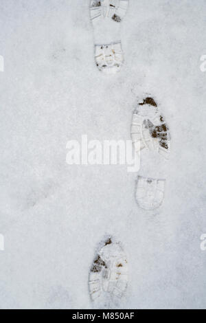 Boot prints on a garden path in the snow. UK Stock Photo