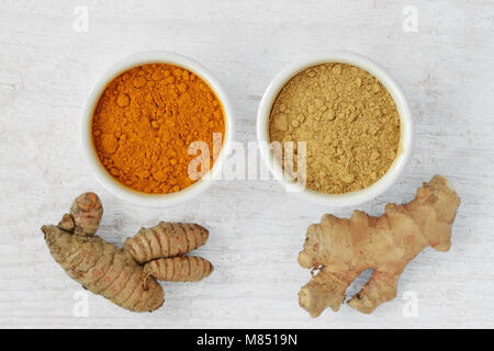 Powder and roots of turmeric and ginger on wooden background Stock Photo
