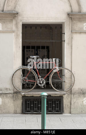 Bicycle left on windowsill in narrow old street to save the street space Stock Photo