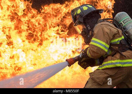 Senior Airman Eric Poole, 374th Civil Engineer Squadron firefighter, battles a simulated aircraft fire during live-fire training at Yokota Air Base, Japan, March 8, 2018. Aircraft live-fire training is conducted periodically throughout the year to ensure Airmen and civilians with the 374th CES and 374th Maintenance Squadron repair and reclamation section are always prepared to combat aircraft fuel fires. (U.S. Air Force photo by Yasuo Osakabe) Stock Photo