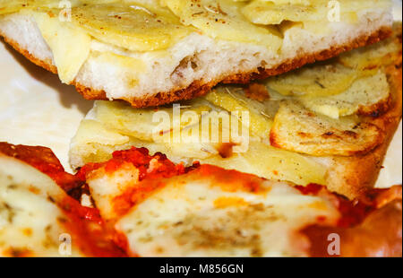 close up of two slices of pizza with tomato, mozzarella and potatoes Stock Photo