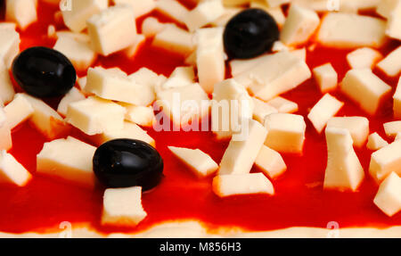 Raw pizza decorated mozzarella, black olives and tomato sauce ready to be baked Stock Photo