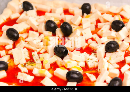 Raw pizza decorated mozzarella, black olives and tomato sauce ready to be baked Stock Photo