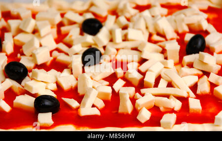 Raw pizza decorated mozzarella, black olives and tomato sauce ready to be baked Stock Photo