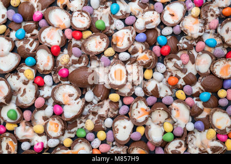 Have a smashing Easter.  Smashed Cadburys creme eggs with chocolate mini eggs on a slate background Stock Photo