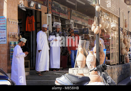 Sur, Oman, January 1.2014: Discussing traders in front of a row of shops selling souvenirs for tourists, middle east Stock Photo