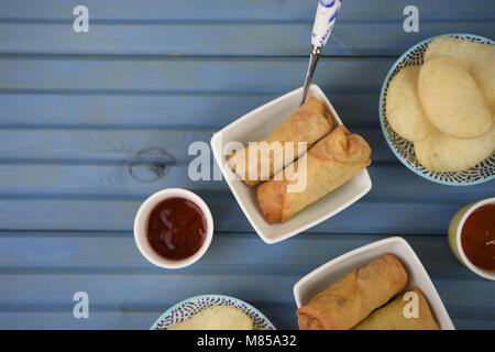 flat lay table of food of prawn crackers and spring rolls with dipping sauce Stock Photo