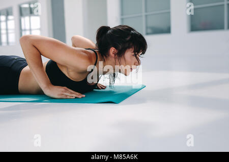 Strong woman doing push ups in gym. fitness female working out on yoga mat in health club. Stock Photo