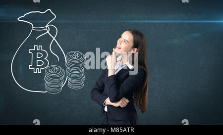 Beauty business woman standing near btc logo. Succesful Bitcoin investment. Concept of virtual criptocurrency. Stock Photo