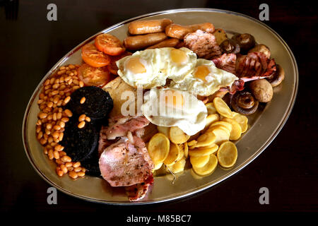A MEGA fried Full English breakfast cointaining fried eggs, Black Pudding, Mushrooms, Bacon, Sausages, Baked Beans, Toast, Tomatos and potato slices. Stock Photo
