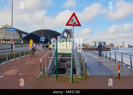 Cycle lanes next to the IJ river with Amsterdam Central Station in the background, Amsterdam, Netherlands Stock Photo