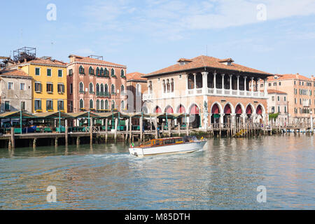 Water taxi passing Rialto Fish Market, Grand Canal in early morning  light, San Polo, Venice,  Veneto, Italy with reflections on the water Stock Photo