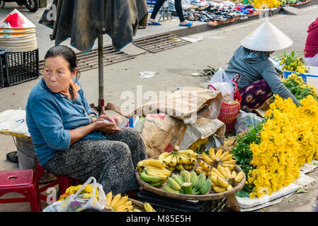 A woman sells bananas on the street at an outdoor market in Hoi An, Vietnam Stock Photo